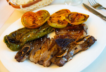 Spanish cuisine. Appetizing grilled beef spare ribs with garnish of grilled vegetables