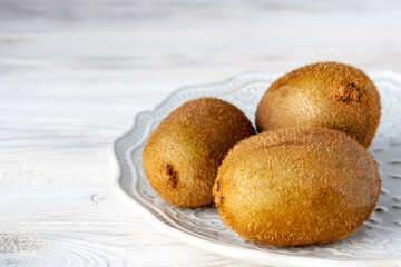 ripe kiwis lie on a white ceramic plate, selective focus, copy space