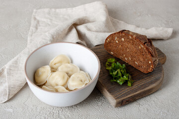 dumplings, rye bread, greens on a wooden board