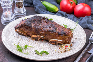 beef ribs on bone on grey plate on dark stone table