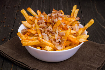 French fries with bacon on bowl on black wooden table