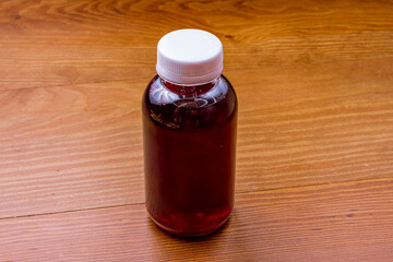 a bottle of red compote on wooden table side view