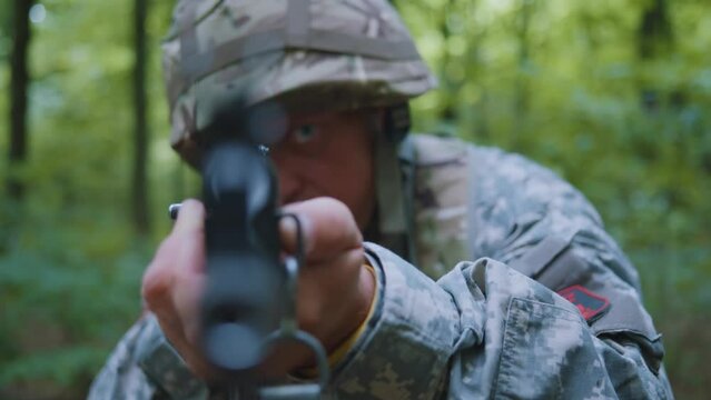 Close up soldiers holding machine gun forward to attack enemy in forest. Machine gun barrel look at camera.