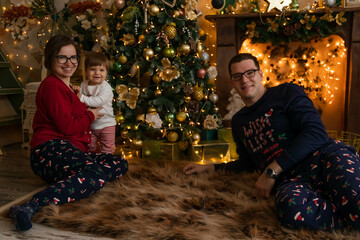 parents and son are playing near the Christmas tree and fireplace