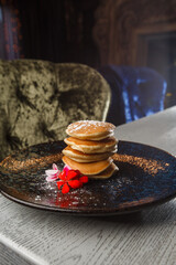 American pancakes with berries and maple syrup on black plate isolated on dark background. cafe menu