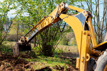 Bucket excavator at work in the countryside in a private yard. .Digging the ground, clearing land and landscaping works with specialized machinery.