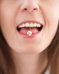 Fototapeta premium close up of a woman eating flowers. Woman holding flowers in her mouth. Lilies of the valley