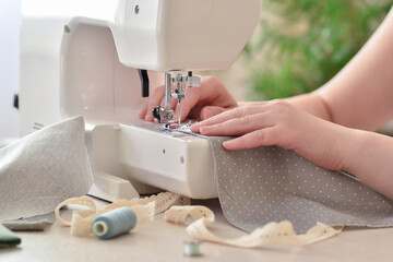 Close-up of women's hands that sew on a sewing machine