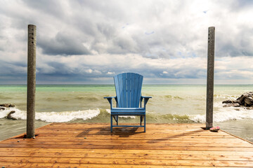 A place to sit and think.  An Adirondack (or Muskoka) chair sits on a simple wooden deck in spring....