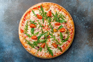 Pizza with seafood and aragula with tomatoes and cheese top view on dark blue stone table