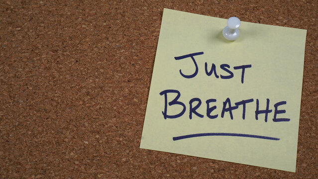 Note pinned to a cork board with a reminder to just breathe.