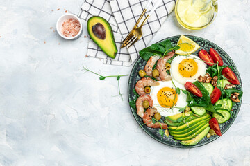 shrimps, prawns, soft fried egg, fresh salad, tomatoes, cucumbers and avocado on a light background. Ketogenic diet breakfast. Keto, paleo lunch. Top view