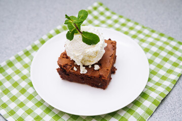 Fototapeta na wymiar brownie portion with a ball of vanilla ice-cream on top. American traditional pastry. Cocoa powder and chocolate are main ingredients.