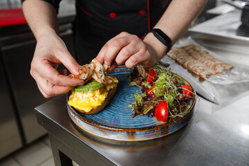Chef pouring unagi sauce on toast. Buckwheat bread toast with an scrambled egg, a sliced avocado, a eel, tomatoes and lettuce. Dietary menu. Flat lay