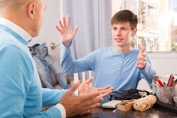 Portrait of teen boy having conversation with man in home interior