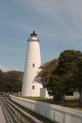 White Ocracoke Lighthouse with Windows, Sky, Greenery on Sunny Day
