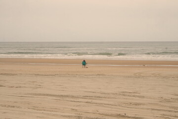 Fototapeta na wymiar Woman Sitting in Beach Chair on Sandy Beach, Ocean and Sky in Daylight