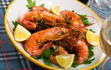 Grilled shrimps served with parsley and lemon on white plate