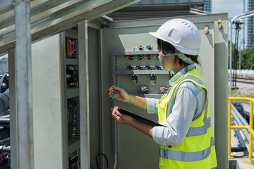 Engineer woman  onsite check control panel waste water treatment plant. Young woman  service...