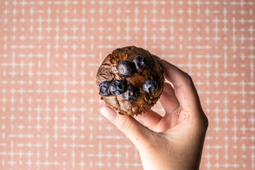 hand of unknown woman hold fresh baked muffin with chocolate cream and blueberries in female hand copy space