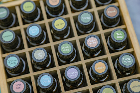 Top-down view of essential oil bottles in wooden storage box with colorful cap stickers