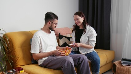 A happy young woman sits down with her man and shows a positive pregnancy test. A young family. Early pregnancy