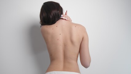 Rear view of a naked woman standing on a white background. A woman lets her hair down. Naked woman