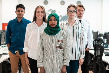 Portrait of young excited multiethnics business team of software developers standing and looking at camera at modern startup office