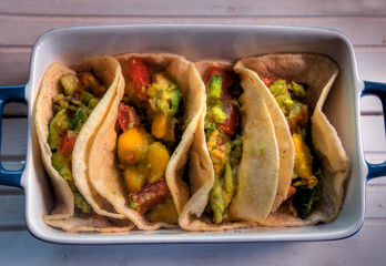 Top view of tacos with mango, avocado, jalapeno, tomato and red onion