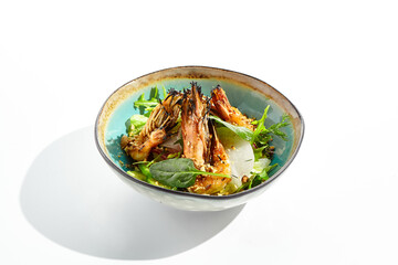 Green salad with grilled prawns and vegetables. Healthy food in restaurant menu. Shrimp with salad mix and peanuts - delicious dish for keto diet. Restaurant dish isolated on white background.
