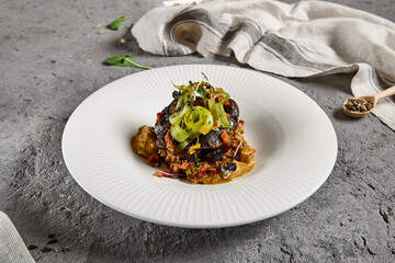 Braised beef cheeks with pearl barley and celery in creamy mushroom sauce. Veal cheek with mushroom risotto on gray stone background. Main course concept. Food menu for restaurant.