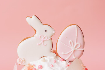 Bunny and egg cookies on top of cake against pink background.