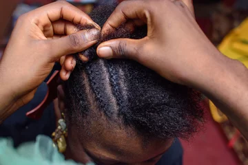 Selbstklebende Fototapeten Friseursalon Hands of an african Nigerian hair dresser or stylist making weaving hairstyle for a client in saloon  © kehinde