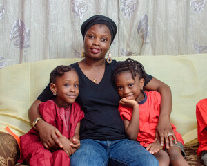 Lovely african Nigerian family consisting of a mother or guardian and her children, sitting closely...