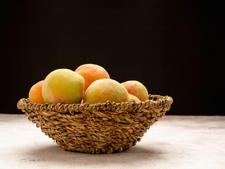 Group of fresh peaches fruits in a basket on a black background