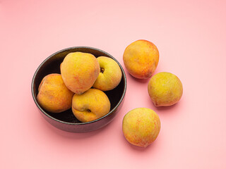 Group of fresh peaches fruit in a bowl on a pink background