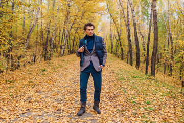 Tall handsome man walking in the autumn alley