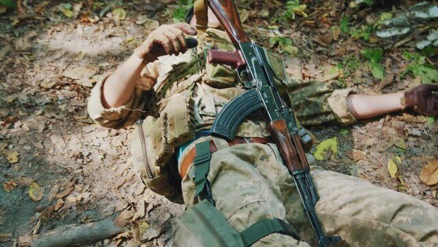 In dense forest soldier wounded or died lying on ground. War. Military concept. With rifle