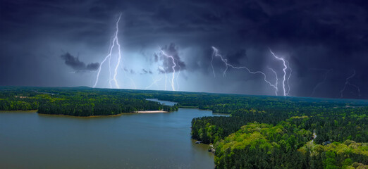 a gorgeous aerial panoramic shot of the rippling blue lake with vast miles of lush green trees with powerful storm clouds and lightning at Dallas Landing Park in Acworth Georgia USA