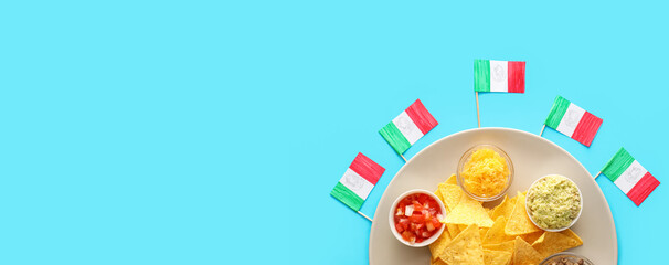 Plate with traditional Mexican food and flags on blue background with space for text