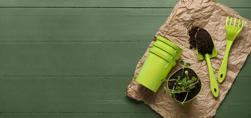 Seedlings with soil and gardening tools on color wooden background with space for text