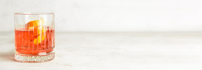 Glass of tasty Negroni cocktail on light background with space for text