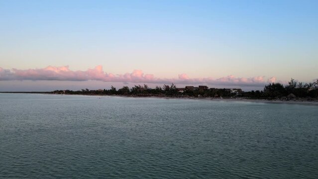 Wide angle drone shot during sunset with beautiful pink hues in the clouds located on the tropical island of Holbox in the Caribbean sea in Mexico shot in 4k.