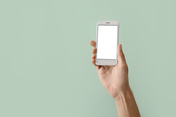 Male hand with modern mobile phone on color background