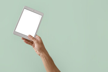 Male hand with modern tablet computer on color background