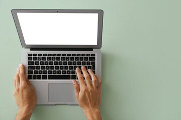 Male hands with modern laptop on color background