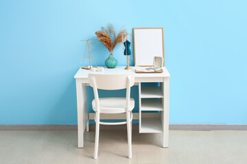 Table with jewellery and chair near color wall in room