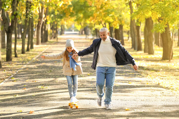 Little girl with her grandfather skating in park