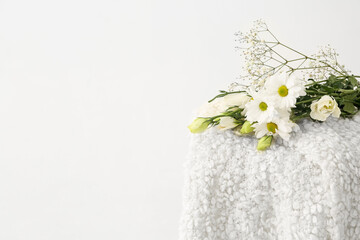 Stool with warm blanket and flowers on white background