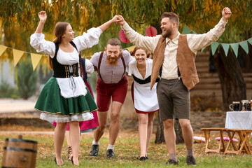 Drunk people dancing and celebrating Octoberfest outdoors - obrazy, fototapety, plakaty